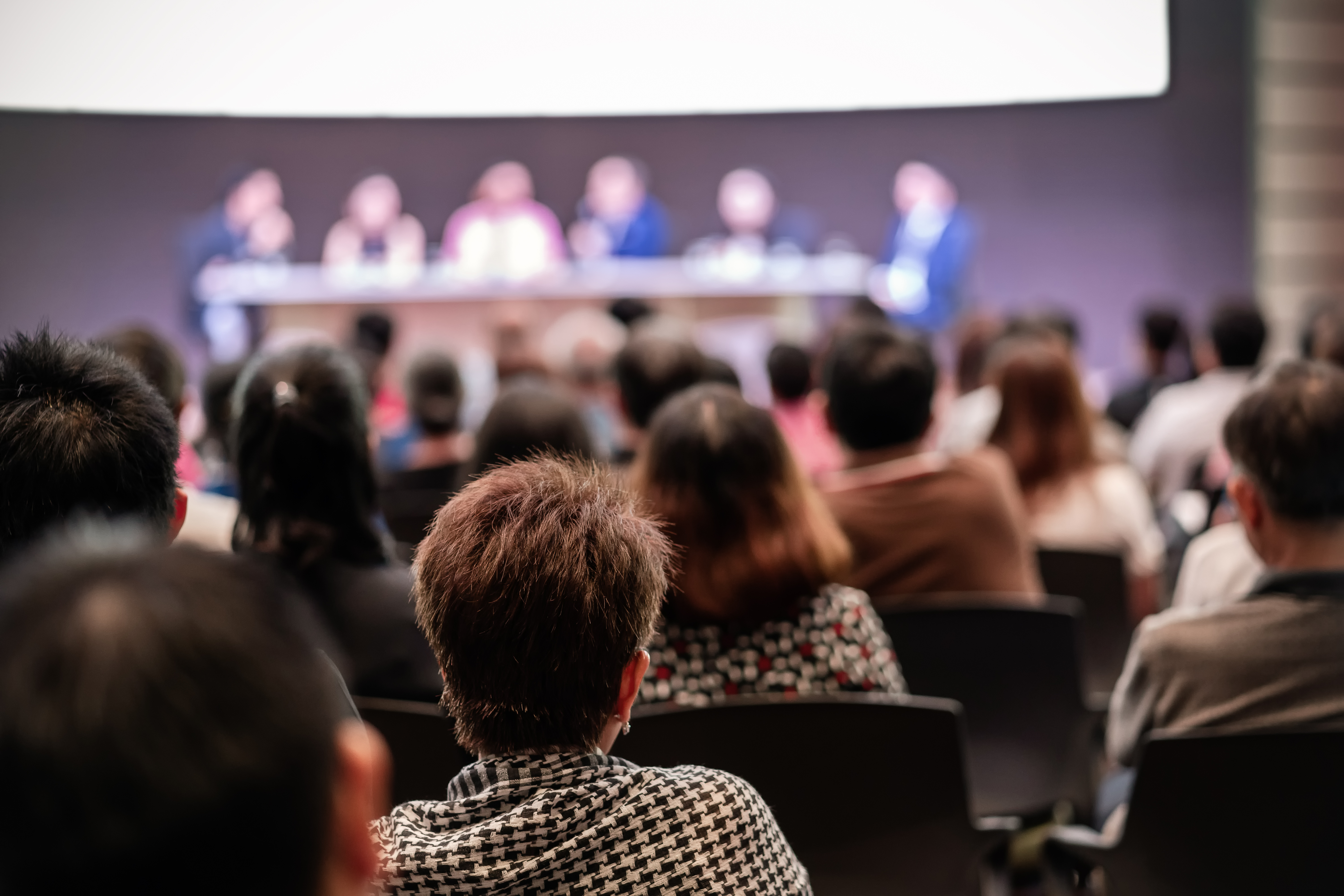 Rear view of Audience in the conference hall or seminar meeting which have Speakers are Brainstorming and talking on the stage, business and education about investment concept